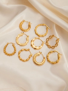 Detail view of nine assorted vintage gold titanium steel hoop earrings on white silk