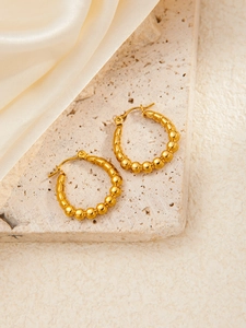 Macro shot of gold plated titanium steel hoop earrings with bead texture on stone