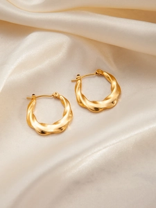 Detailed view of French vintage twisted gold hoop earrings on champagne silk background