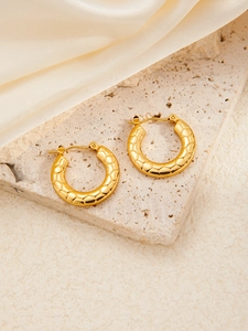 Detailed close-up of gold titanium hoop earrings with textured honeycomb pattern