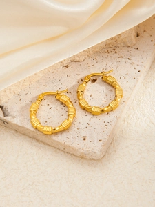 Macro view of gold plated titanium steel hoop earrings with bamboo texture on stone
