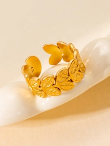 Macro shot of gold-plated leaf ring with detailed veins on a curved ceramic stand