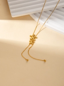 Detail von doppelten goldenen Blumenanhängern an einer Y-Halskette aus Edelstahl