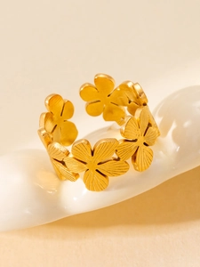 Macro shot of gold floral open ring featuring textured five-petal flower engravings