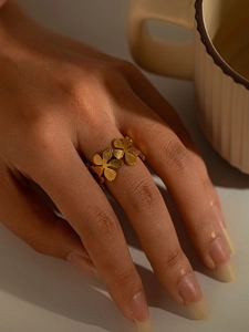 Detail of a gold titanium steel floral ring featuring engraved four-petal flower patterns