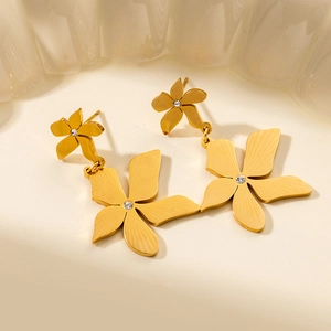 Macro shot of gold floral earrings with brushed texture and central zircon crystal
