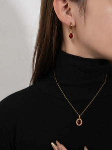 Details von luxuriösem Goldschmuck-Set mit roten ovalen Steinen und Zirkonia-Akzenten