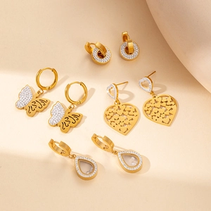 Detail of four gold-tone titanium steel earrings including heart and butterfly designs