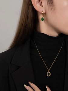 Modell trägt Goldschmuckset mit ovalem grünem Zirkon und Diamant-Heiligenschein