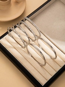 Collection of five assorted silver-toned titanium bracelets in a velvet jewelry box