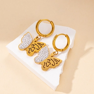 Detail of gold butterfly drop earrings with cubic zirconia inlay and scrollwork design