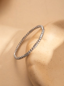 Macro detail of silver-tone textured beads and long tube links on a sleek steel bracelet