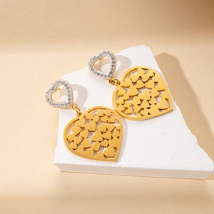 Detailed close-up of gold heart earrings with hollow pattern and sparkling rhinestone inlay