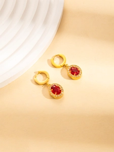 Details von goldenen Huggie-Ohrringen mit rotem ovalem Edelstein und Zirkonia-Halo