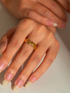 Macro detail of gold-plated stainless steel twisted ring with a polished layered design