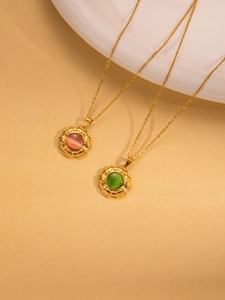 Detailopname van gouden titanium stalen kettingen met roze en groene edelsteen hangers