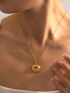 Detail van gouden titanium ketting met roze kattenoogsteen hanger om de hals