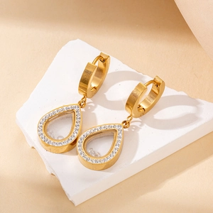 Detailed macro view of gold heart hollow earrings with sparkling crystals on stone