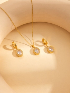 Makroaufnahme von Goldschmuck-Set mit ovalen Anhängern und Ohrringen auf beigem Dekor