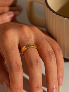 Close-up of gold titanium steel multi-layer stacked ring on a finger with warm aesthetic