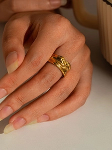 Detail of a wide gold titanium steel ring with an irregular liquid metal ripple design