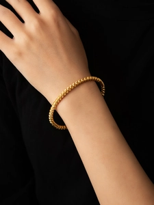 Detail of a thin 18K gold plated beaded titanium bracelet with fine spiral textures