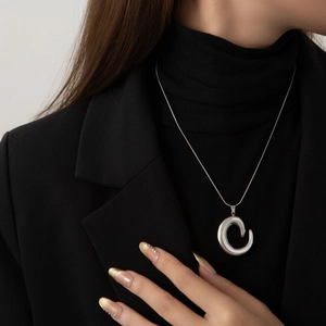 Elegant silver stainless steel necklace with large C-shaped pendant on black suit