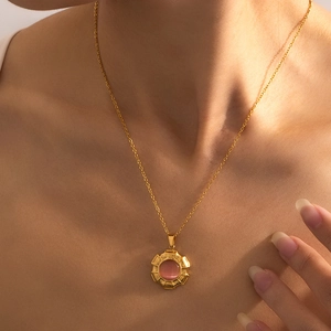 Elegante gouden titanium ketting met een ronde hanger van roze kattenoogsteen
