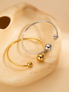 Detail of minimalist gold and silver titanium steel open bangles on a ceramic tray