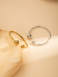 Detailed shot of gold and silver steel bangles with polished asymmetric metal spheres