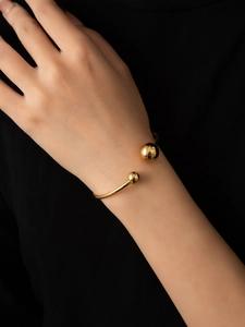 Detail of 18K gold-plated titanium cuff bracelet with polished dual metal spheres