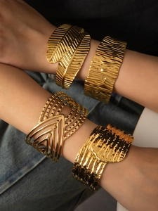 Detail of four gold-plated textured open cuff bracelets with wave and feather patterns