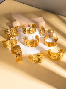 Detailed view of varied gold cuff bracelets with hammered and bohemian textures