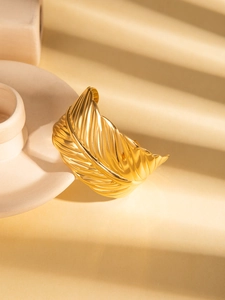 Detail of gold titanium steel open bangle with intricate tropical leaf vein textures