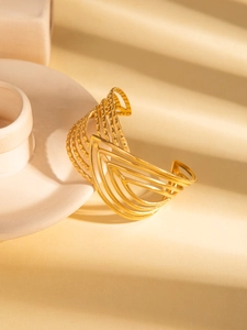 Detail of a wide gold-plated stainless steel cuff with geometric multi-layer texture