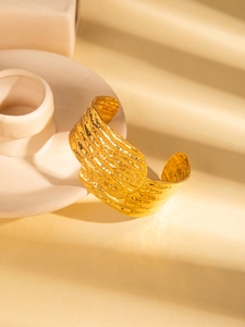 Detailed view of wide gold-plated steel cuff featuring textured hammered finish
