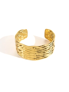Macro detail of gold wide cuff bracelet with wavy 3D textured folds and polished finish