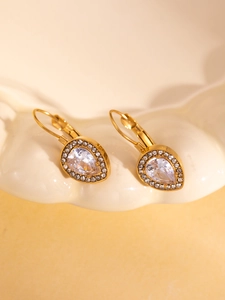 Detailed close-up of gold pear-shaped drop earrings with clear zircon on a ceramic dish