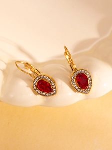 Detail of vintage teardrop earrings with red pear-cut stone and gold lever-back setting