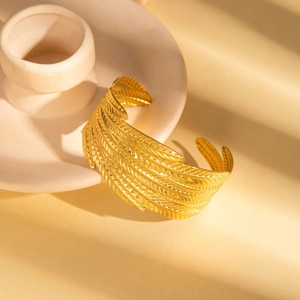 Gold plated titanium steel cuff bracelet featuring detailed feather texture on stone