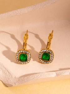 Detailed shot of vintage gold earrings with emerald green square stones and micro-pave