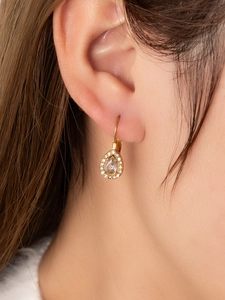 Macro shot of gold-plated teardrop earrings with crystals and zircon for a vintage look