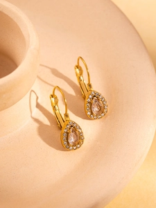 Close-up of elegant gold pear-shaped drop earrings with sparkling zircon gemstones