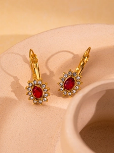Close-up of vintage gold leverback earrings featuring red oval gems and crystal halo