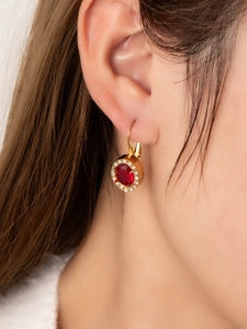 Close-up of vintage 18K gold plated drop earrings with red oval gems worn by a model