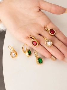 Macro shot of 18K gold plated leverback earrings with oval red, green, and white gemstones