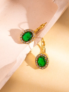 Detail of vintage 18K gold plated earrings with large oval green stone and halo crystals