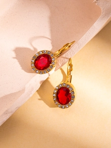 Close-up of vintage gold lever-back earrings with oval red gems and white rhinestones