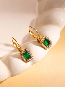 Detailed close-up of vintage leverback earrings with emerald cut green stones and gold plating