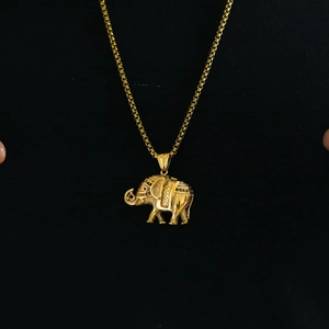 Close-up of golden elephant pendant with intricate patterns on a black background